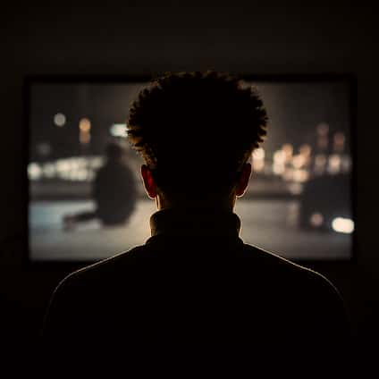 A person watching a projected scene in a dark room