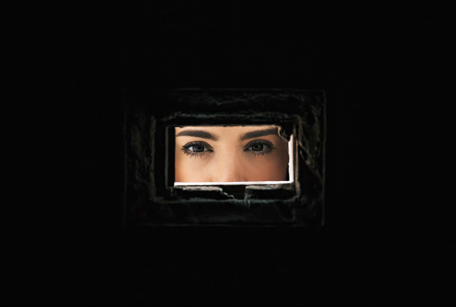 A woman's eyes seen through a narrow rectangular opening