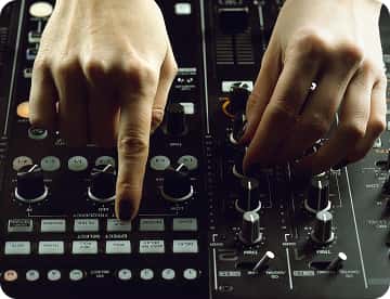 Hands adjusting controls on an audio mixing console